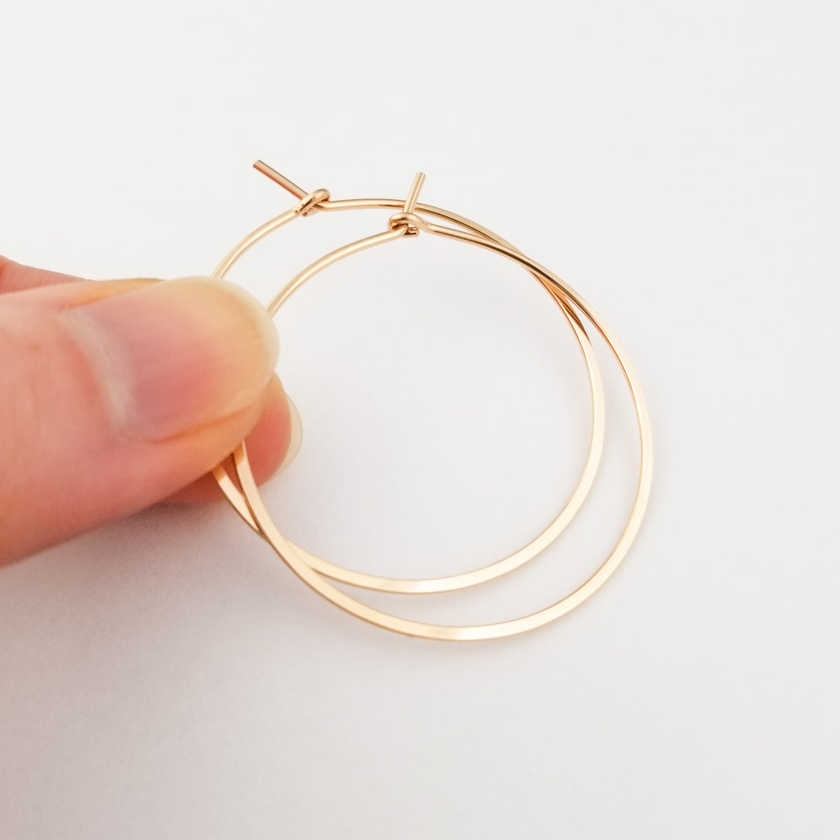 Round Rose Gold Hoops Hammered Flat Held in Fingers