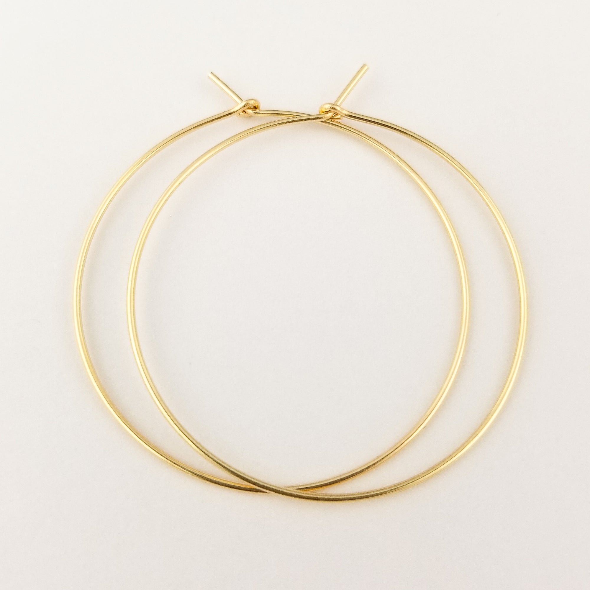 Thin Solid Gold Hoop Earrings Handmade with 14 Karat Yellow Gold Held in Fingers