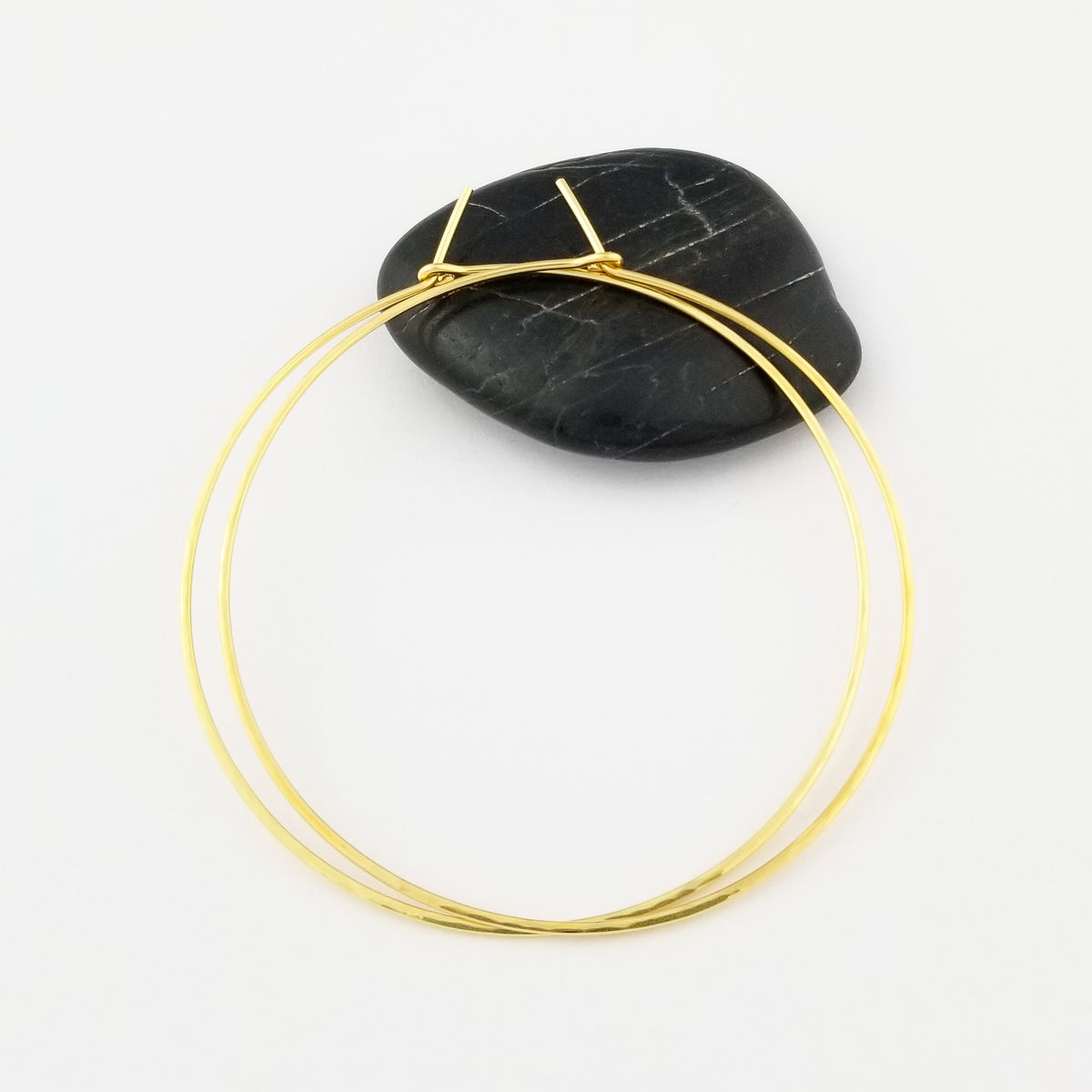 Large Two Inch Lightly Hammered Gold Hoop Earrings on Black Rock