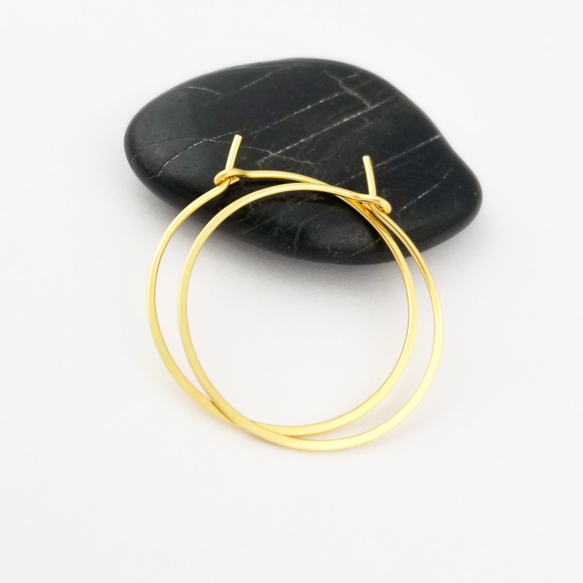 Solid Gold Hoops Hammered Flat Made from Solid 18k Yellow Gold sitting on Black Rock