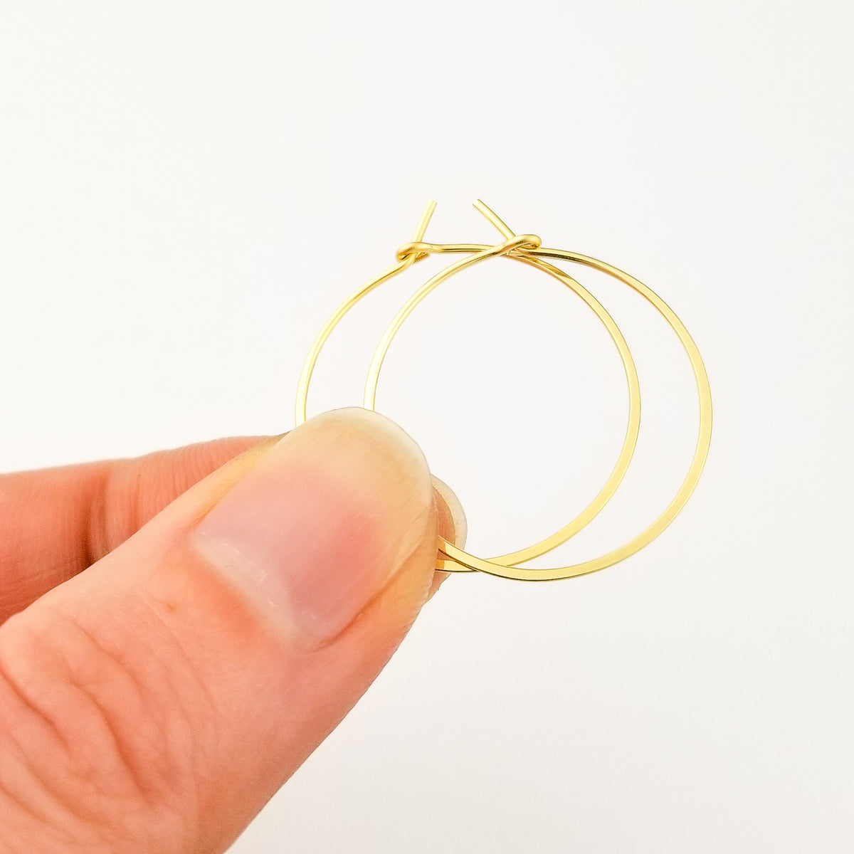 Gold Hoop Earrings Held in Fingers