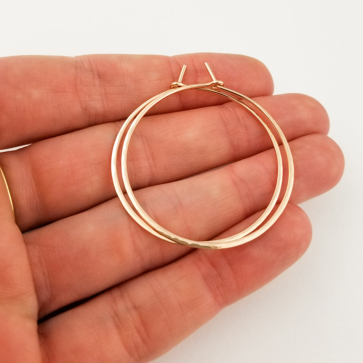 Solid Gold Thick Hammered Hoop Earrings in 14 Karat Rose Gold Held in Hand