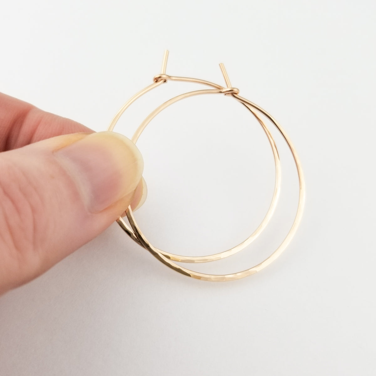 Hammered Gold Hoop Earrings in Solid 14 Karat Rose Gold Thick Metal Wire Held in Fingers